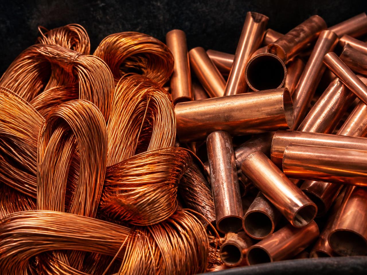 Sorted bare bright copper wire and clean copper pipe in a yard bin